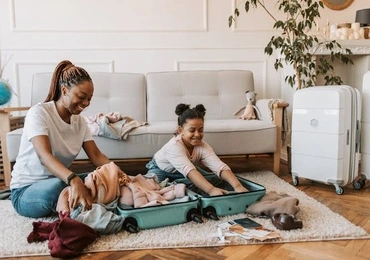 mother and daughter packing a bag for travel, holding a passport.