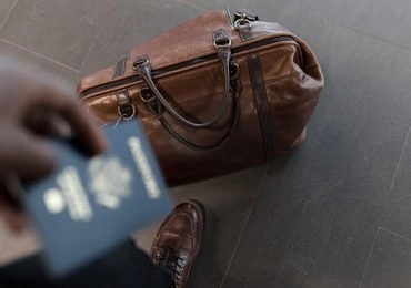 passenger holding a passport and a travel bag