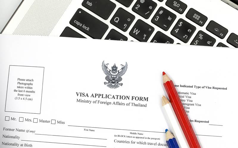 Thailand Visa Application Form with red ,white and blue pencils placed upon It.